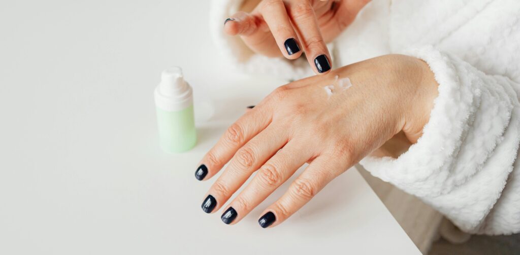 A woman applying a rejuvenating hand cream on the back of her hand, emphasizing skincare for youthful hands. Dr. Tracy Pfeifer, New York, Hamptons